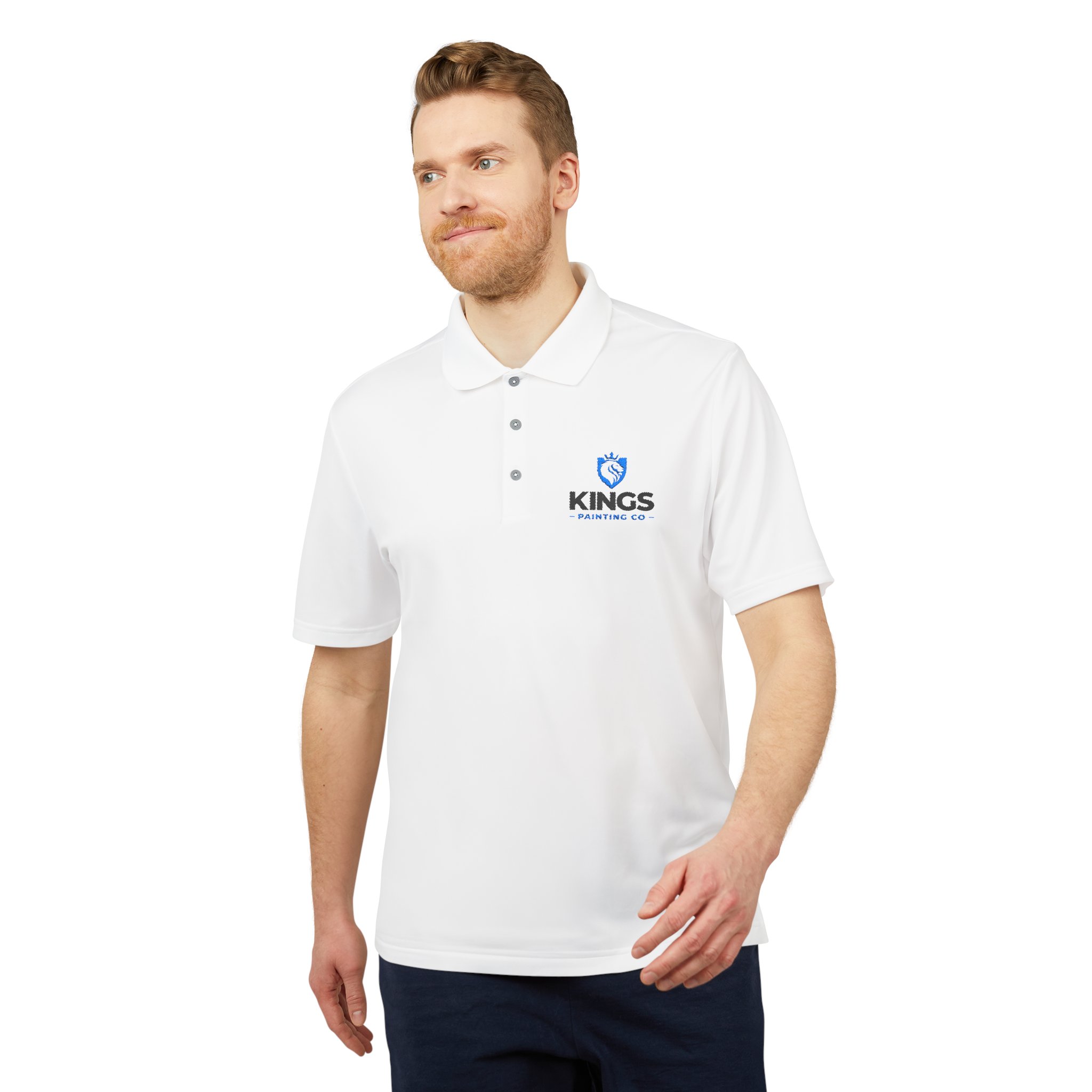 A man with light hair and a beard is standing and looking slightly to the side, wearing a white Kings Painting Co. Performance Polo by Under Armour®, which features the logo on the left chest.